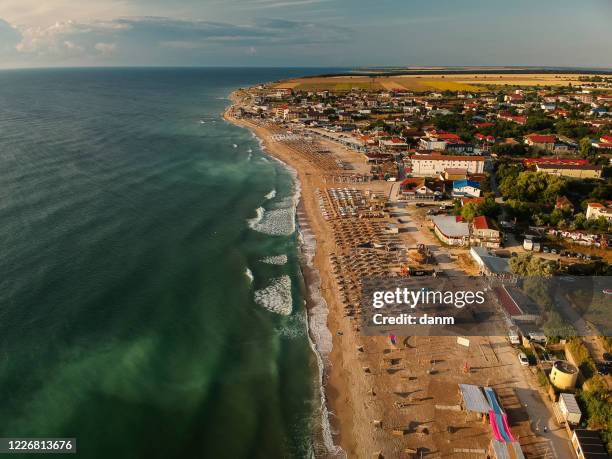 aerial view of amazing beach with umbrellas and turquoise sea at sunrise. black sea at vama veche, romania - romania beach stock pictures, royalty-free photos & images