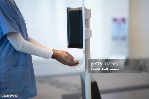 medical professional using a touchless sanitizer dispenser - nurse washing hands stock pictures, royalty-free photos & images
