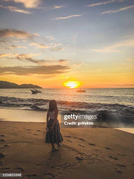 woman watching sunset at the beach in batu ferringhi, penang, malaysia - penang state stock pictures, royalty-free photos & images