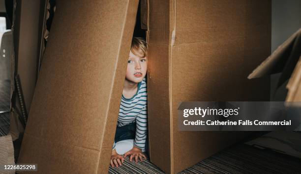 boy playing in cardboard boxes - playhouse stock-fotos und bilder