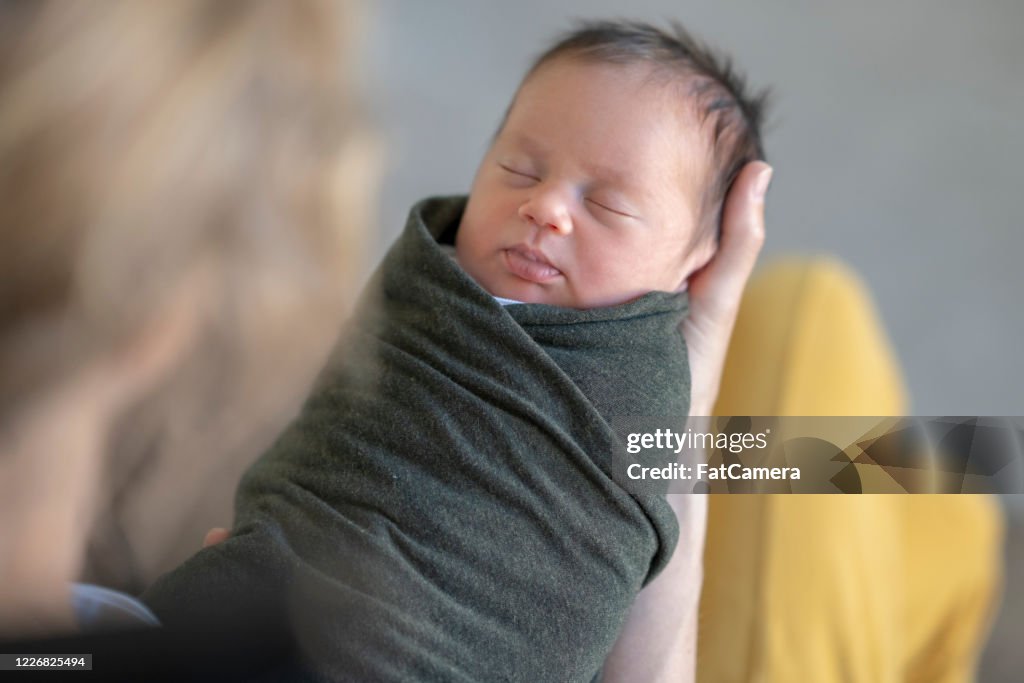 Caucasian mother holding her swaddled newborn