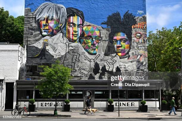 Person wearing a protective mask walks a dog past the Empire Diner in the Chelsea neighborhood of Manhattan during the coronavirus pandemic on May...