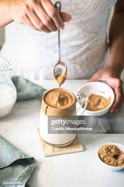 dalgona coffee, a woman in pouring fluffy whipped coffee on milk - recipe imagens e fotografias de stock