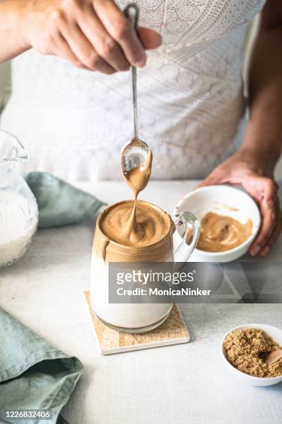 達爾戈納咖啡,一個女人在牛奶上倒著蓬鬆的咖啡 - dalgona 個照片及圖片檔