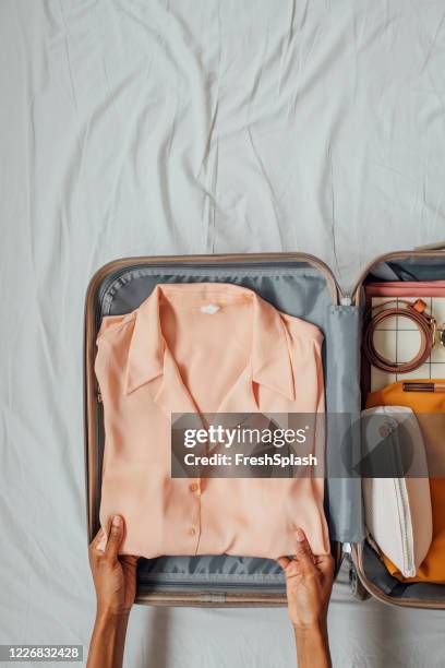 a woman packing her clothes in a suitcase - folded blouse stock pictures, royalty-free photos & images