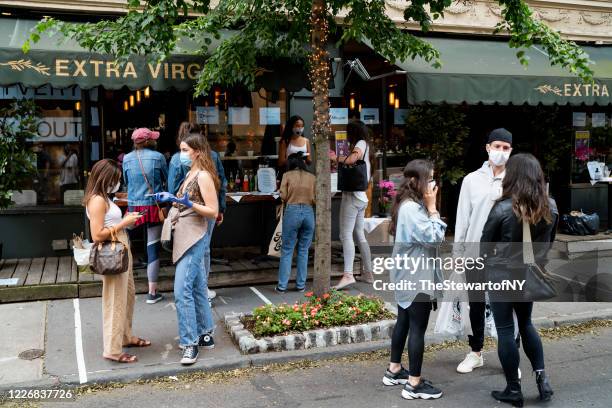 Customers social distance while waiting for orders outside Extra Virgin in the West Village during the coronavirus pandemic on May 24, 2020 in New...