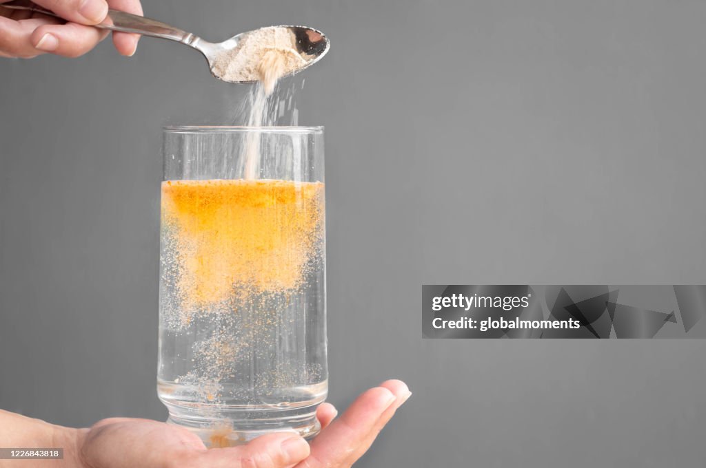 Orange prickelndes Pulver und Wasserglas mit Kopierraum. Gesunde Ergänzung.