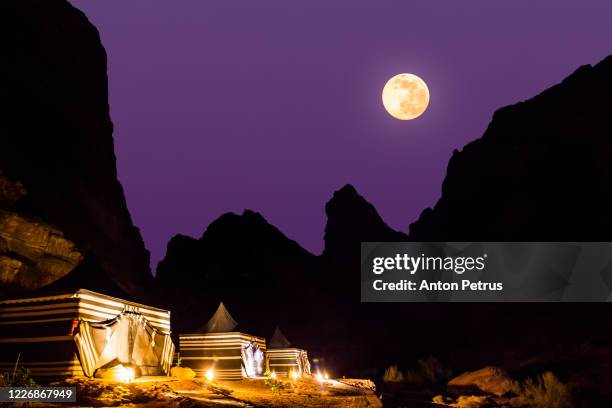 tourist tents in wadi rum desert at dusk with full moon. jordan. - arabian desert adventure night photos et images de collection