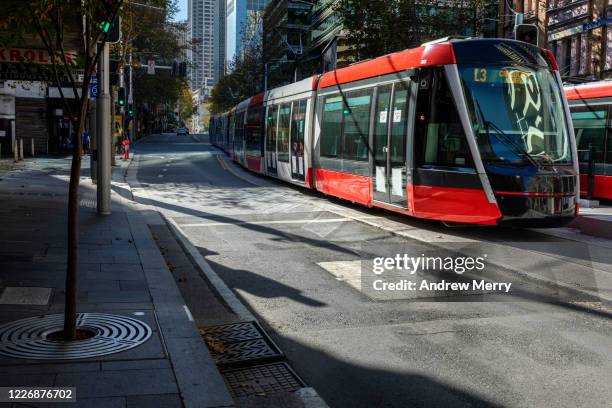 red tram, light rail on empty city street, sydney, australia - street sydney stock pictures, royalty-free photos & images