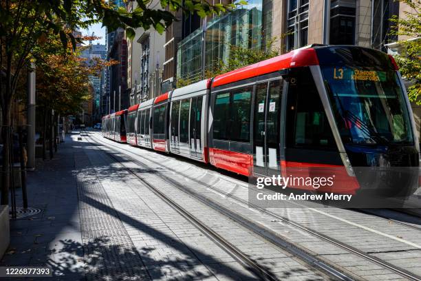 red tram, light rail on empty city street, sydney, australia - lightrail stock-fotos und bilder