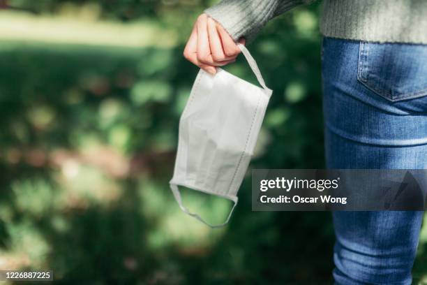 young woman removing protective face mask, walking in nature - removing fotografías e imágenes de stock