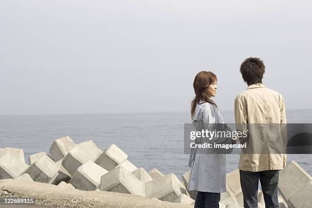 couple standing at river bank - groyne ストックフォトと画像