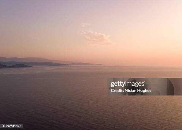 aerial flying over the coast of corsica looking out over the sea at sunrise - corsica beach stock pictures, royalty-free photos & images