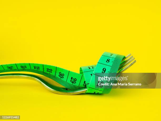 fork and measure tape on yellow background. diet and obesity concept - bulimia 個照片及圖片檔