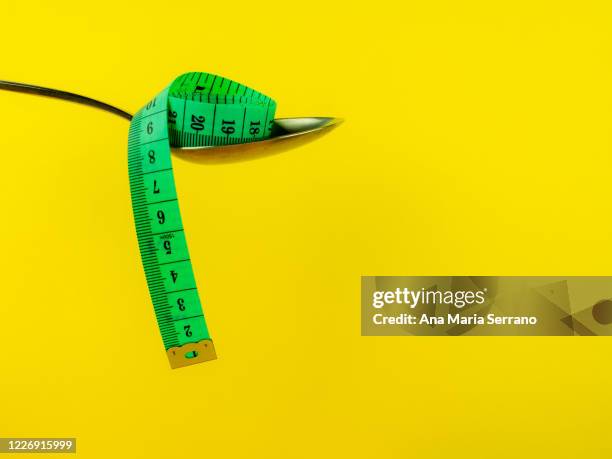 spoon and measure tape on yellow background. diet and obesity concept - anorexie nerveuse photos et images de collection