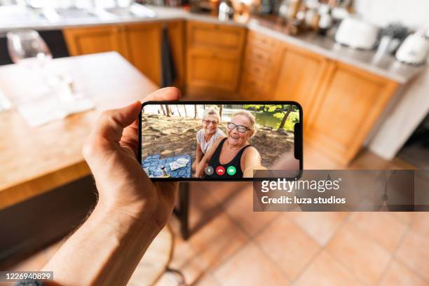 videoanruf mit älteren familienmitgliedern auf dem smartphone - horizontal stock-fotos und bilder