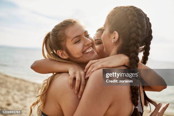 three young women in beach volley team in group hug after scoring - only young women stock pictures, royalty-free photos & images
