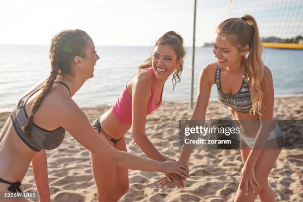 three young women in beach volley team stacking hands for support - beach volleyball team stock pictures, royalty-free photos & images