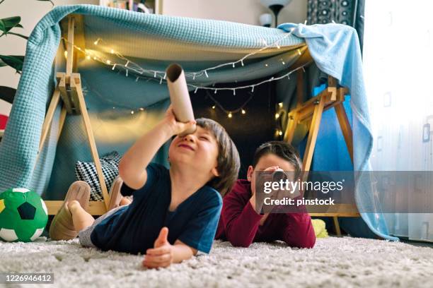 two cute children making a camp and playing together in tent at home - child magnifying glass imagens e fotografias de stock