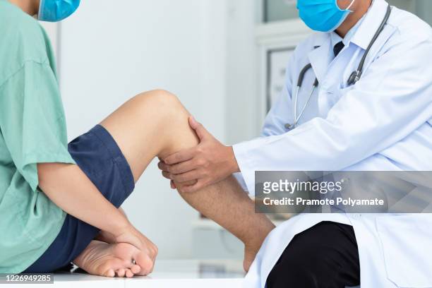 close-up hand doctor examining head of patient with knee problems in clinic. - male feet pics foto e immagini stock