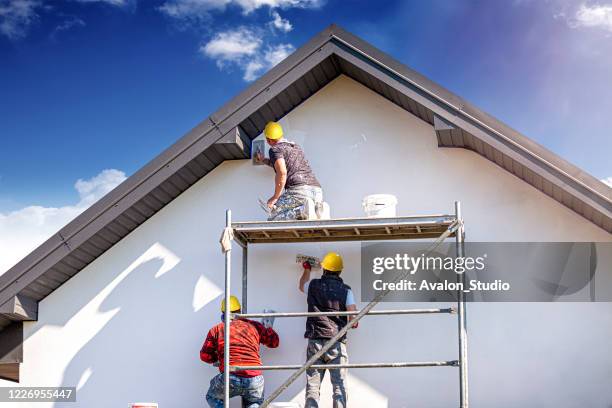 bauarbeiter verputzen die gebäudefassade. - house construction stock-fotos und bilder