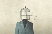 man with open birdcage over his head, surreal freedom concept