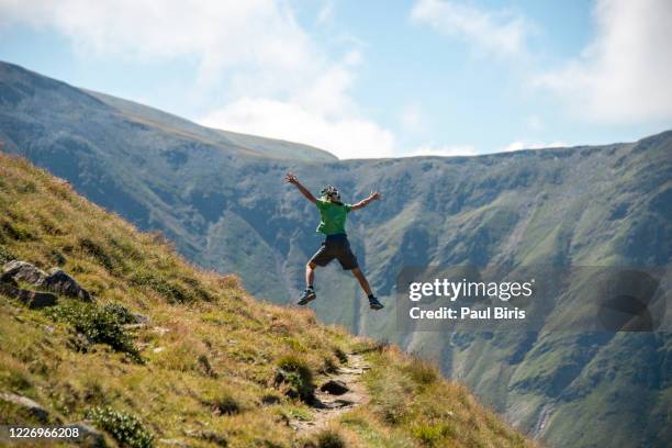 boy jumping on the path to dara peak, fagaras mountains, romania - alps romania stock pictures, royalty-free photos & images