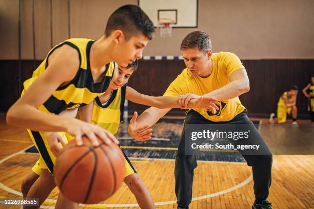 coach training basketball to teenage boys - basketball uniform stock pictures, royalty-free photos & images