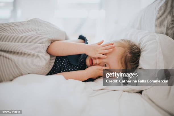 girl covering eyes in bed - child sleeping stock pictures, royalty-free photos & images