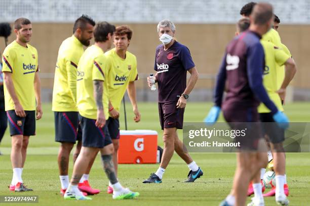 In this handout image provided by FC Barcelona manager Quique Setien gives instructions to his players during a training session on May 25, 2020 in...