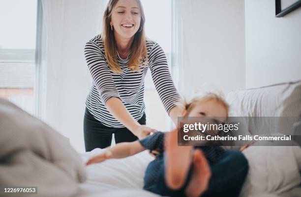 woman and little girl playing on bed - wurf oder sprungdisziplin damen stock-fotos und bilder