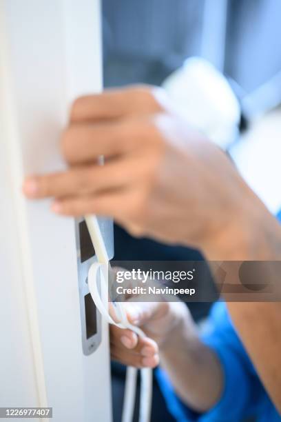 hands installing sound proofing adhesive tape on door frame - isolamento acustico foto e immagini stock