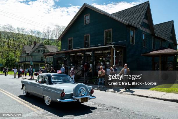 On Memorial Day a historic Ford Thunderbird outfitted with American flags passes a crowd of people cheering them on as they take part in the...