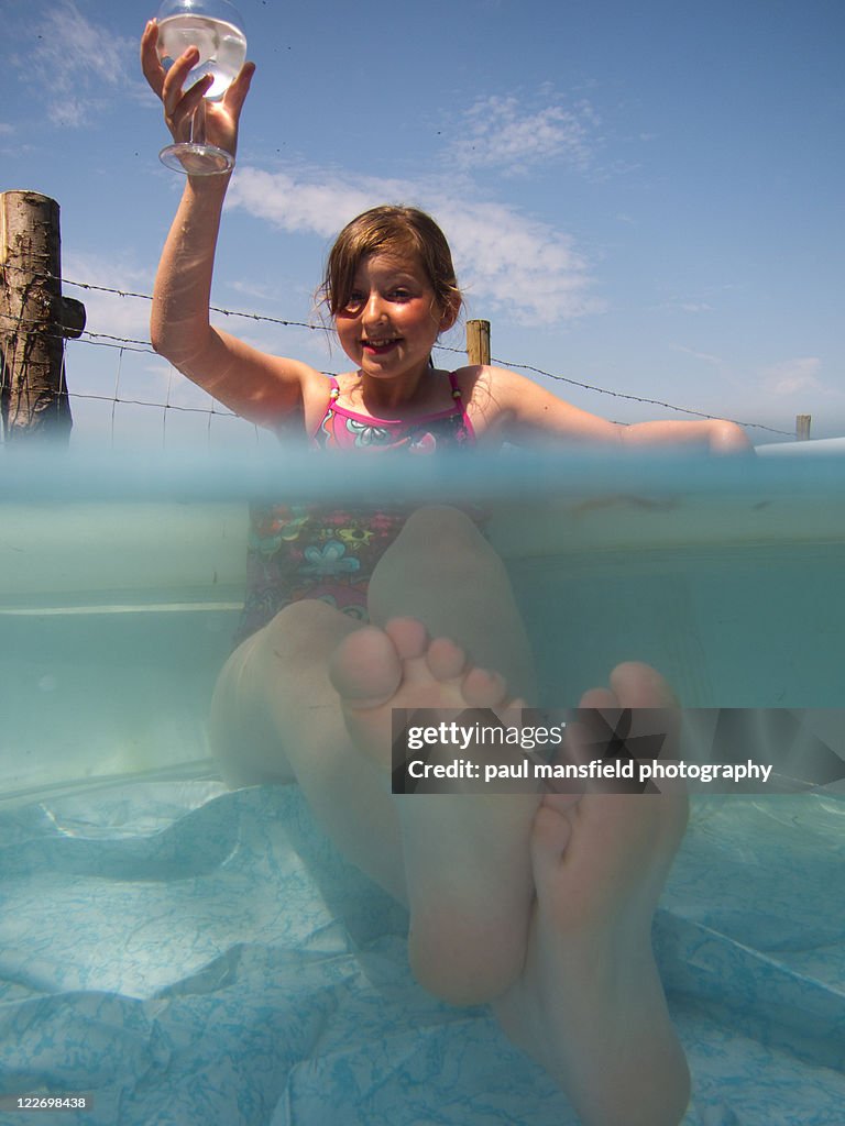 Girl raises glass in paddling pool