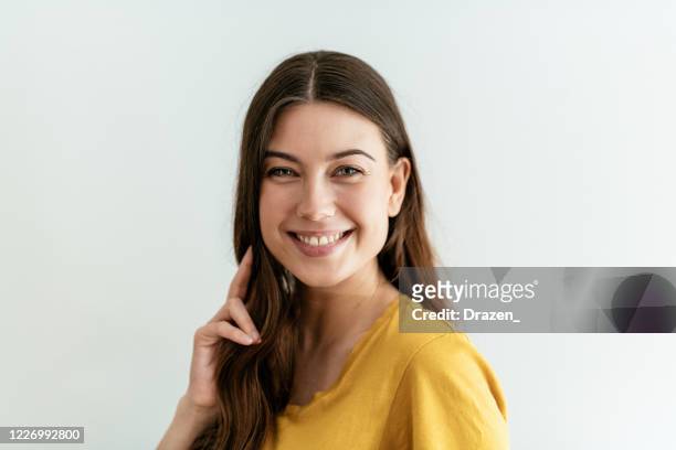 gelukkige jonge vrouw met lang haar in geel t-shirt - no make up stockfoto's en -beelden