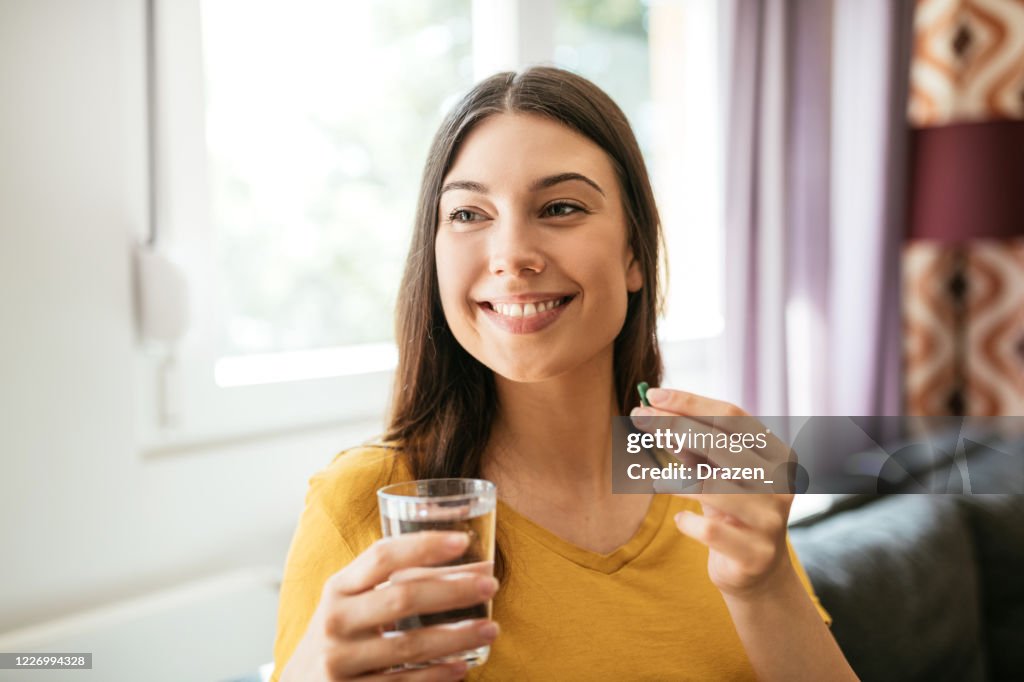 Healthy young woman taking herbal supplements