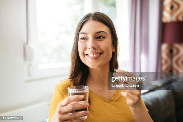 healthy young woman taking herbal supplements - antioxidant stock pictures, royalty-free photos & images