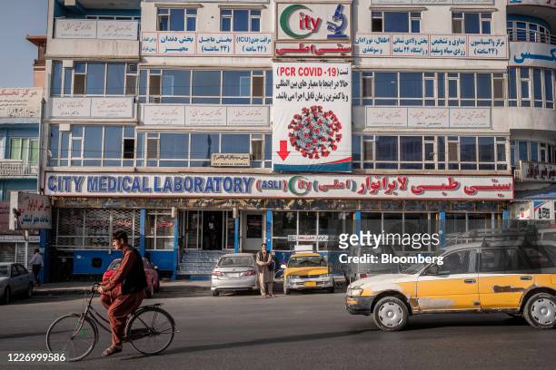 Cyclist and vehicle pass the City Medical Laboratory, home to a Covid-19 testing laboratory, in Kabul, Afghanistan, on Sunday, July 12, 2020....