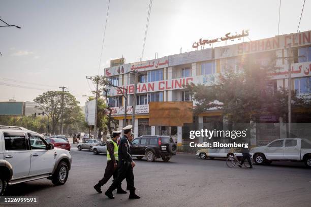 Police officers wear protective masks while walking past the Subhan Clinic, which the Afghanistan health ministry closed down for selling an...