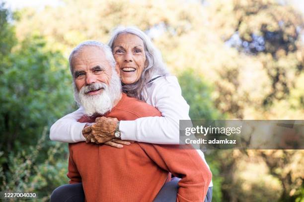 actif senior couple piggyback sur la randonnée de la nature - couple de vieux drole photos et images de collection