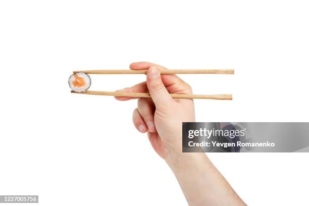 hand holding chopstick with salmon sushi isolated on white background - chopsticks stock-fotos und bilder