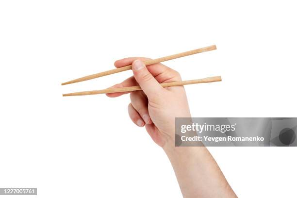 mens hand with chopsticks to eat sushi, isolated on white background - chopsticks stock-fotos und bilder