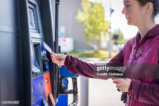 frau zahlt an zapfsäule an tankstelle mit kontaktlosem bezahlen - pumping gas stock-fotos und bilder