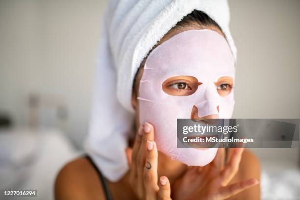 giovane donna latina che applica la maschera facciale - cloth face mask foto e immagini stock