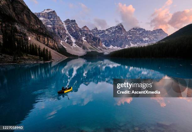 young woman kayaks across mountain lake at sunrise - distance stock pictures, royalty-free photos & images