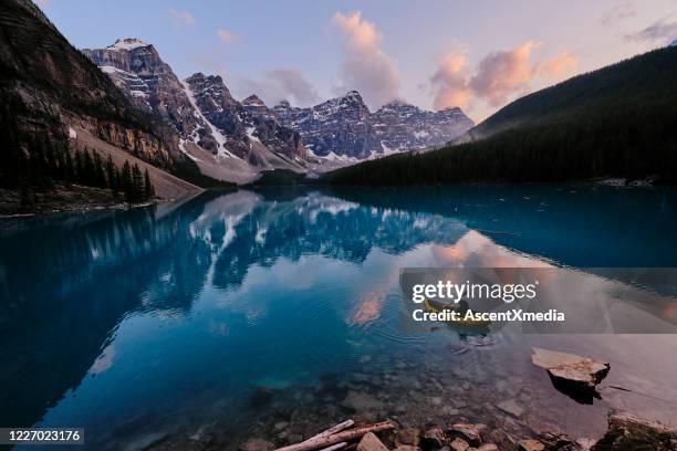 young woman kayaks across mountain lake at sunrise - kayak imagens e fotografias de stock