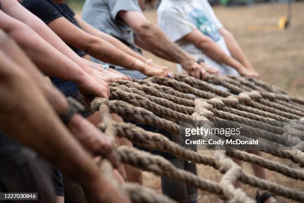 muddy hands holding a rope together - teilnehmen stock-fotos und bilder