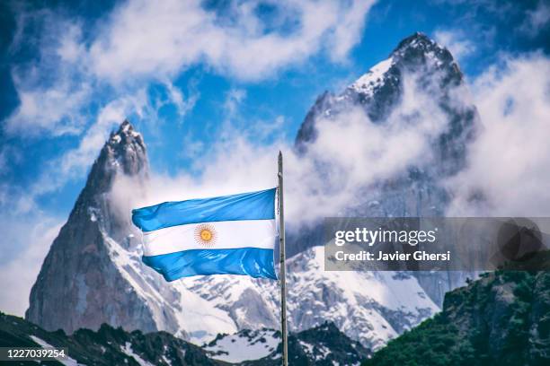 bandera argentina y aguja poincenot (a la izquierda) y cerro chaltén o monte fitz roy (a la derecha), de fondo. santa cruz, argentina. - argentinische flagge stock-fotos und bilder