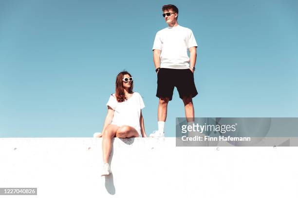 young couple on modern concrete wall urban lifestyle - street style stock pictures, royalty-free photos & images