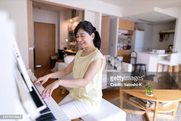 woman playing the piano at home - pianist woman stock pictures, royalty-free photos & images